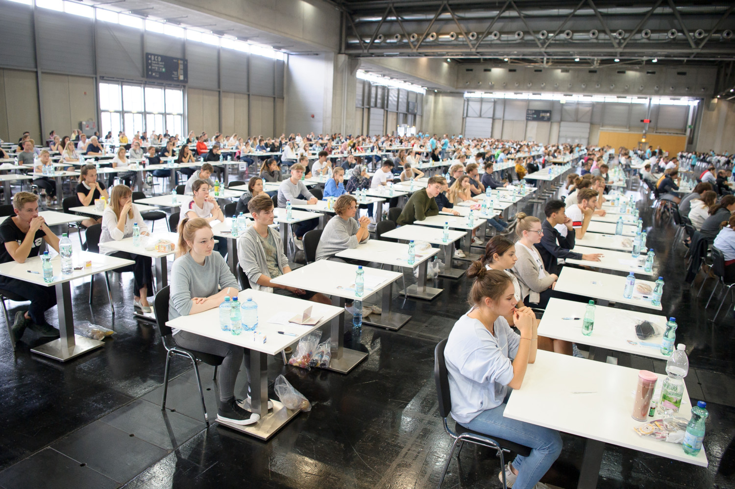 Hundreds of applicants seated at single desks in a large exam hall during the WU Vienna entrance exam